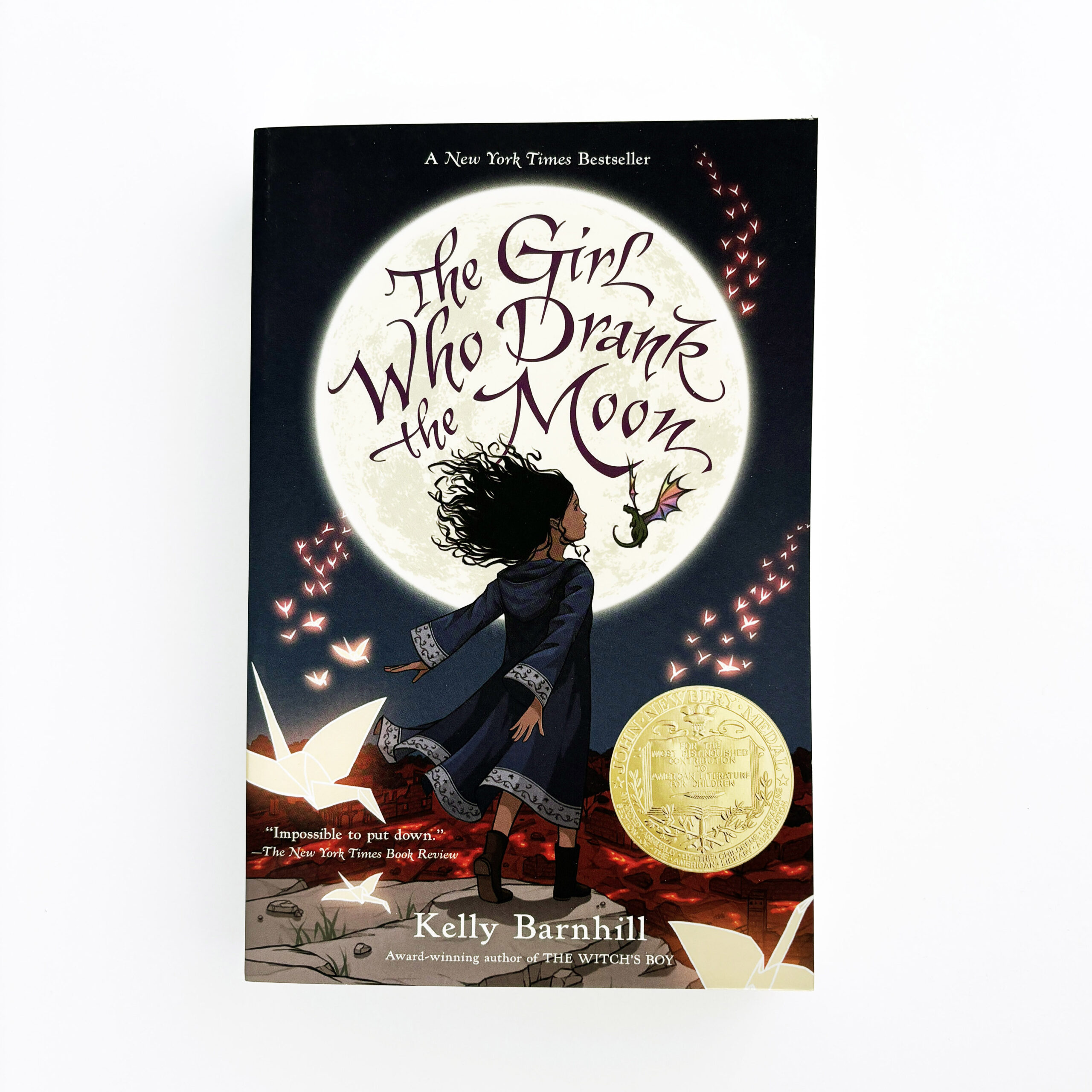 The cover of a book has a young girl in front of a giant moon with a small dragon in the background.