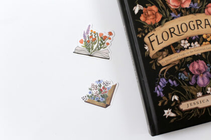 A set of bookish stickers by a book with flowers.